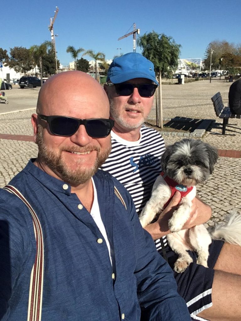 Selfie of a couple, Jean Claude and Marc, with their puppy in Portugal.