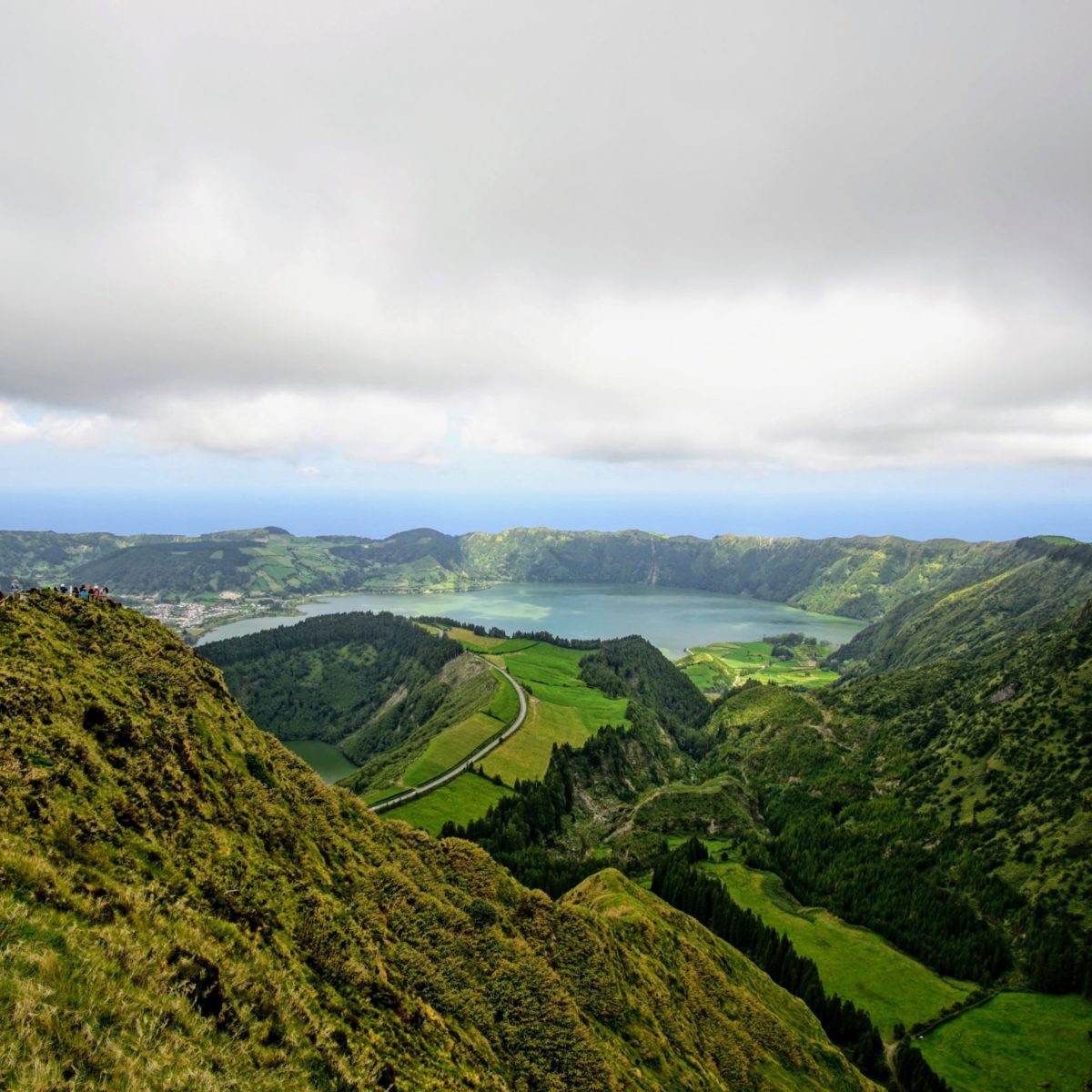 Sky-view of the lush green landscape in Azores Island, with a lake in the middle.