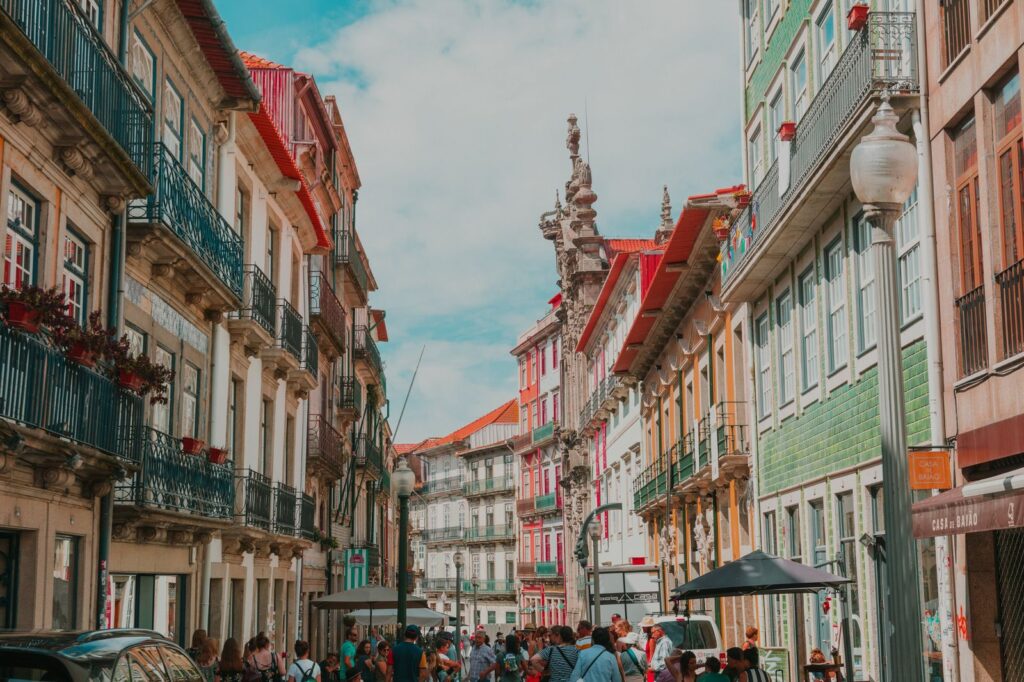 Downtown Lisbon, with lots of colourful buildings in both sides and people walking between them.